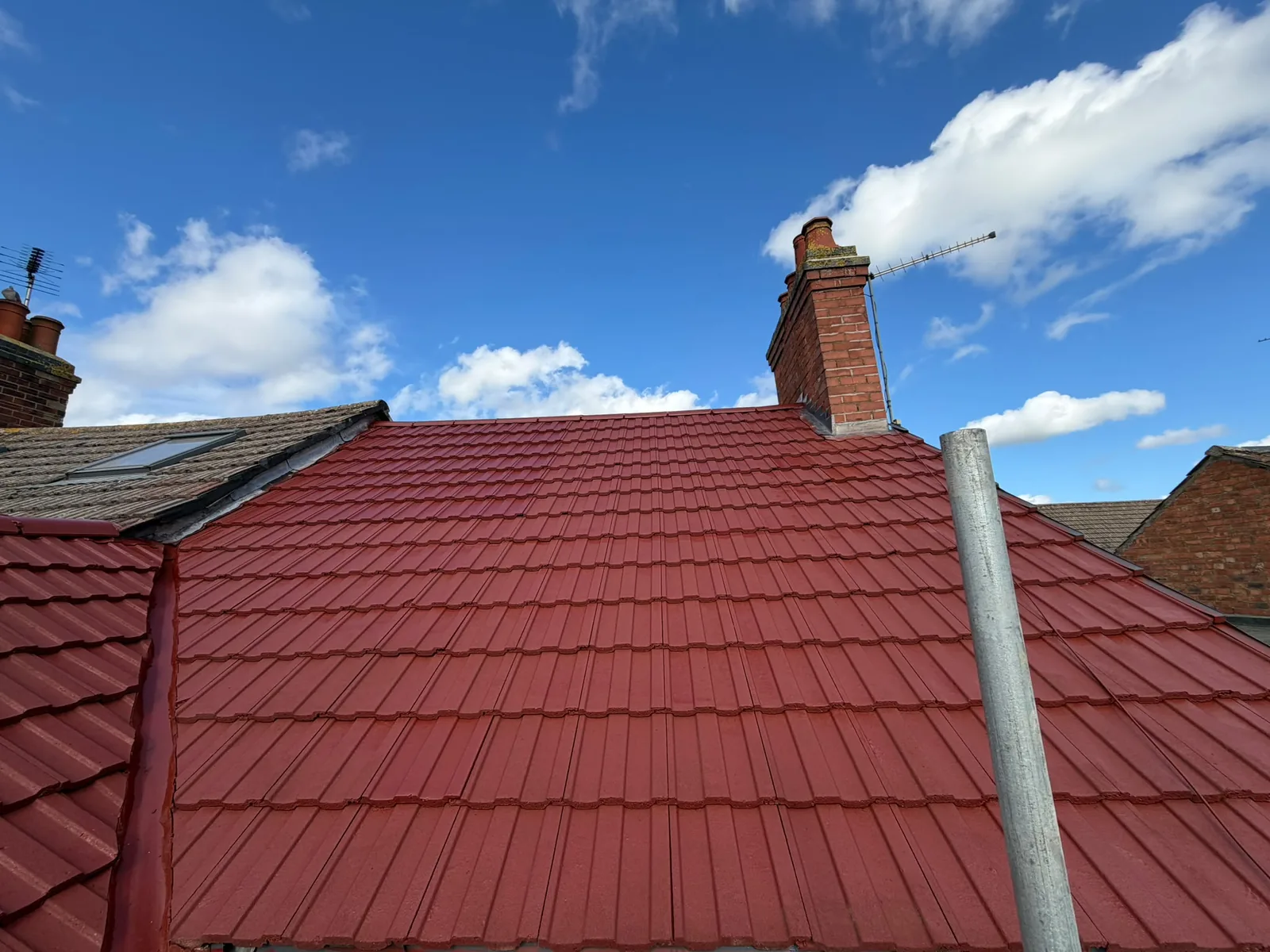 Newly tiled red roof with re-pointed ridge and chimney flashing