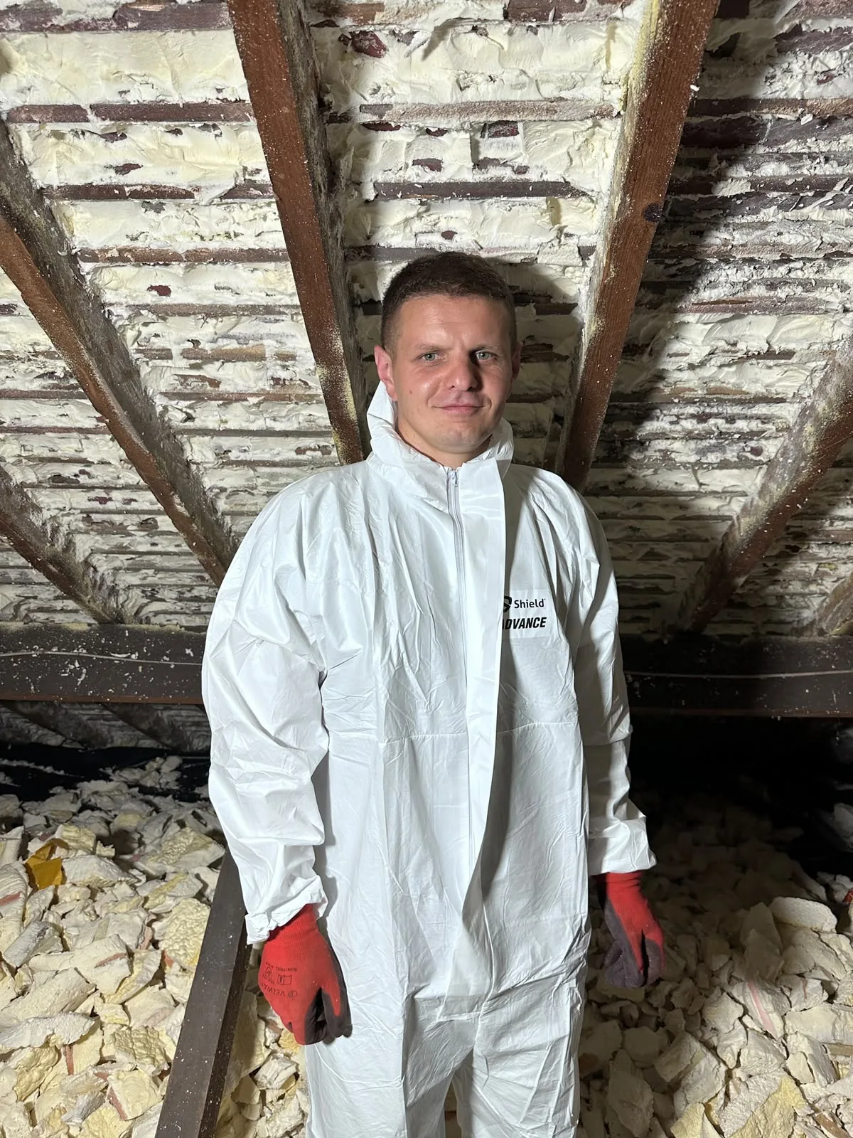 Apex technician in coveralls and gloves standing in a loft