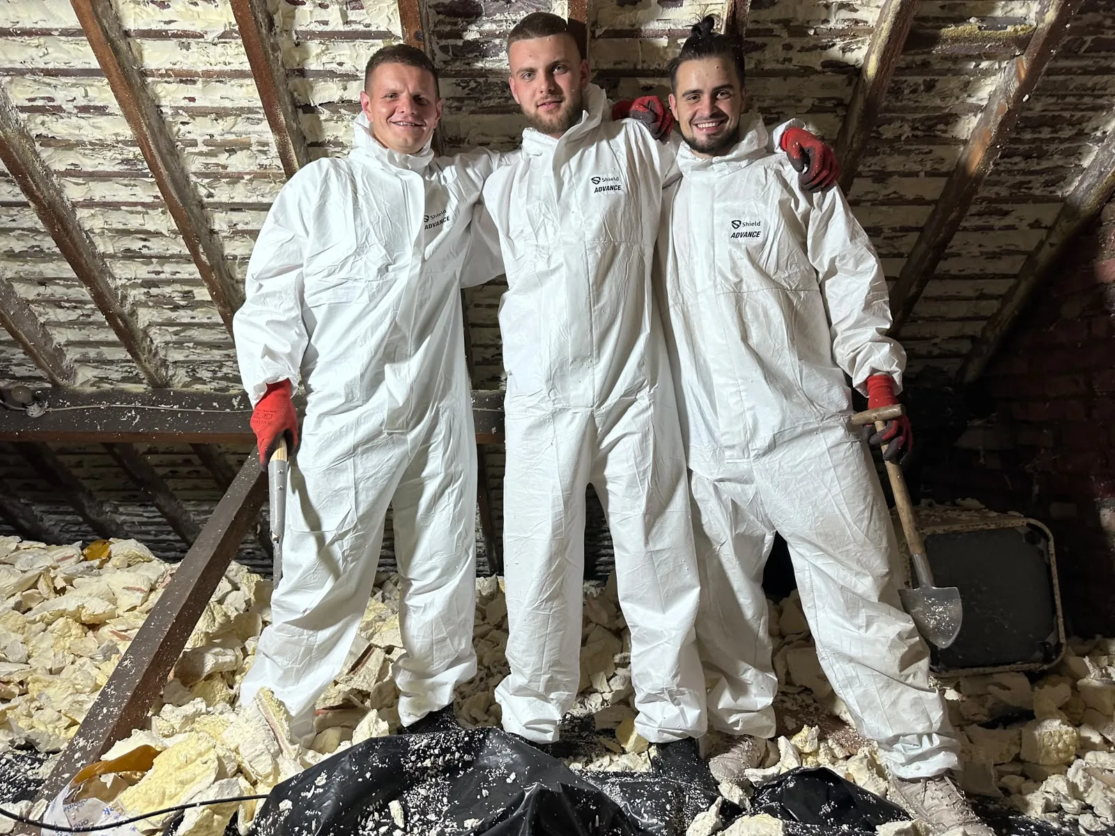 Three Apex technicians in coveralls and gloves on site in a loft